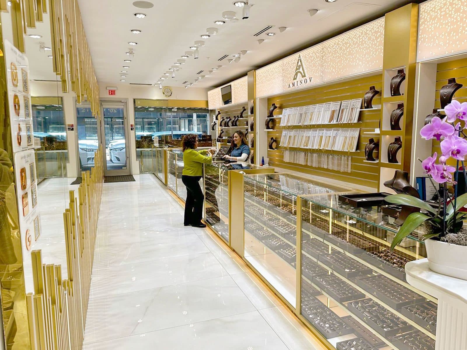 Glass jewelry counters and the gold AMINOV wall in the Aminov Jewelry showroom, looking toward the front door